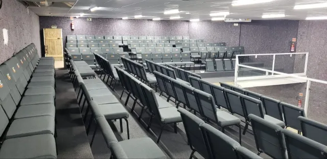 Auditório com cadeiras cinza e fileiras organizadas